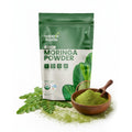 Supple Foods Moringa Powder package with green powder in a wooden bowl on a white background