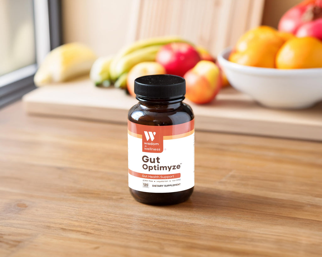 Bottle of Gut Optimize supplement on a wooden surface with fruits in the background